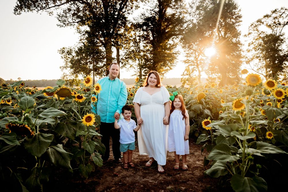 Family portrait session in a blooming sunflower field during golden hour.