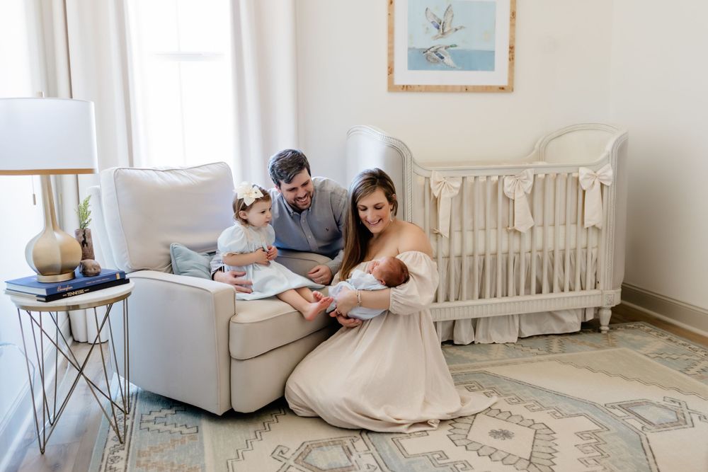 Family reading together in nursery with white crib and modern decor.