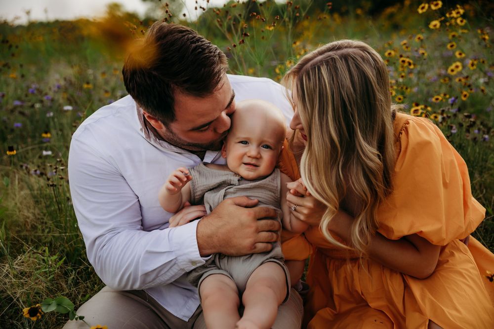 Sweet family moment captured in a wildflower field during sunset.