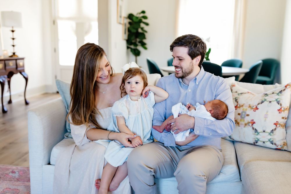 Family sitting together on light blue couch in bright modern living room.