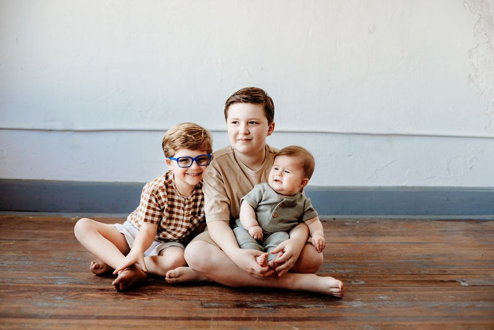A casual indoor family portrait on wooden floors.
