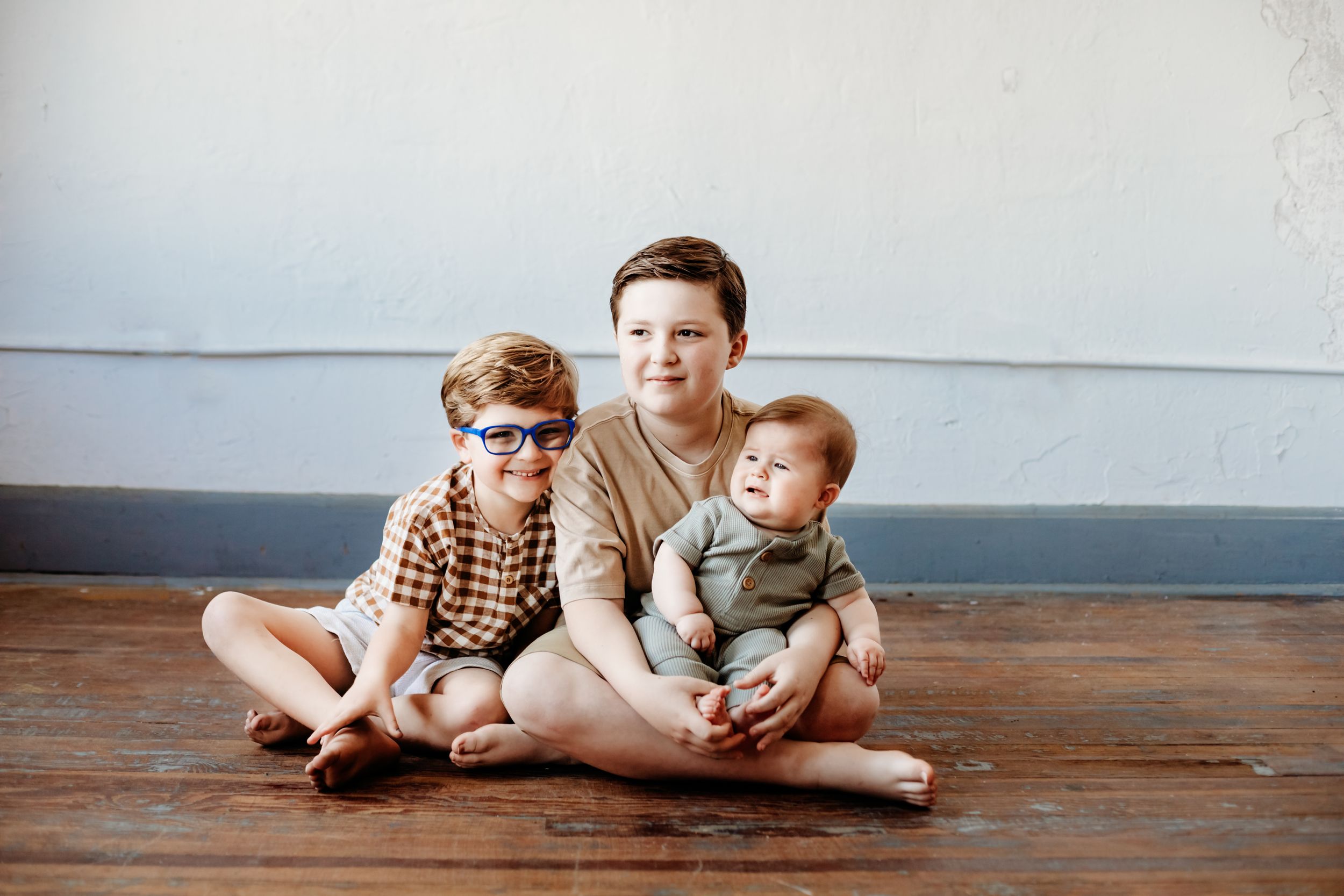A casual indoor family portrait on wooden floors.