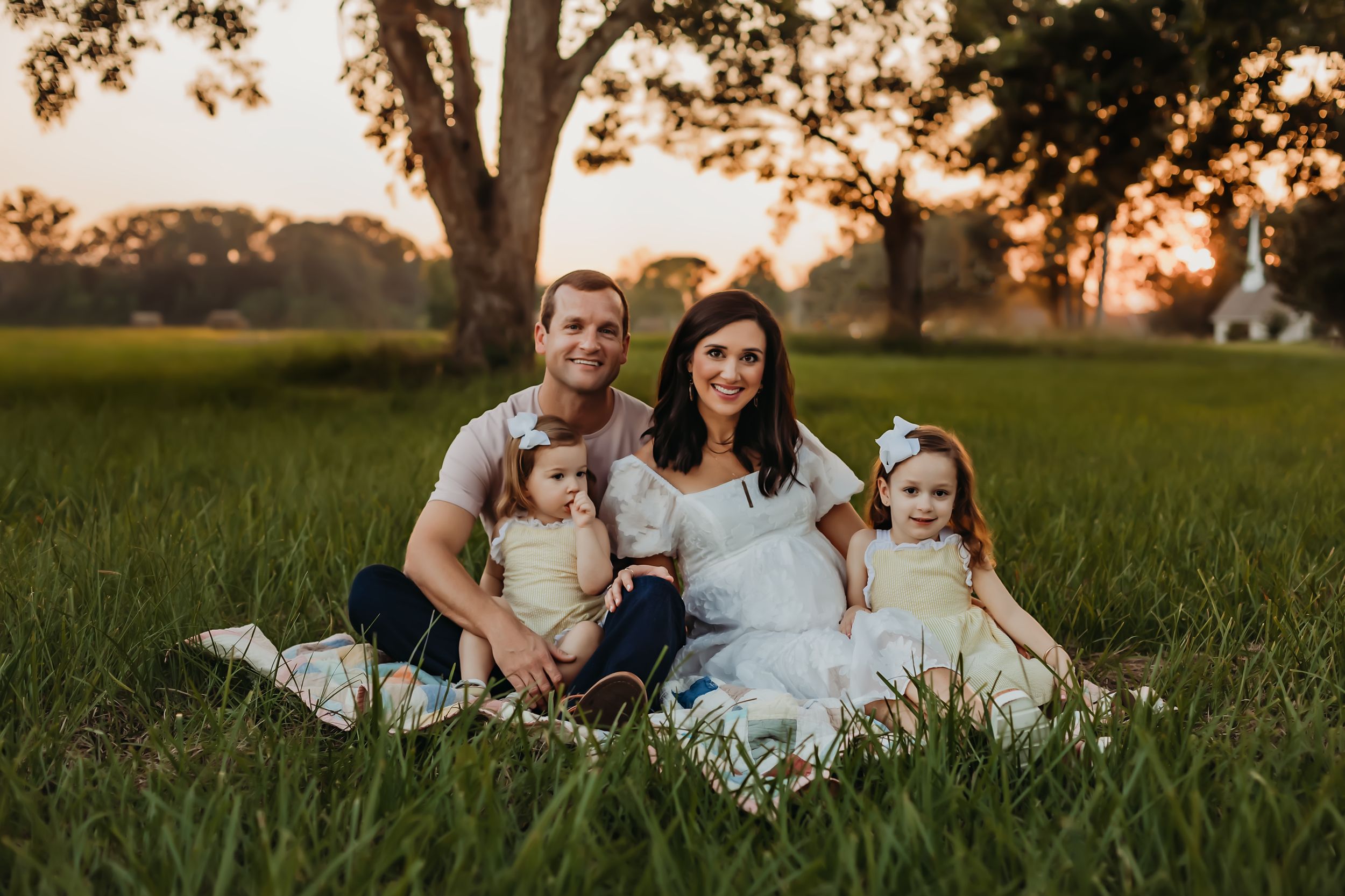 Family sitting together on grass during golden hour portrait session.