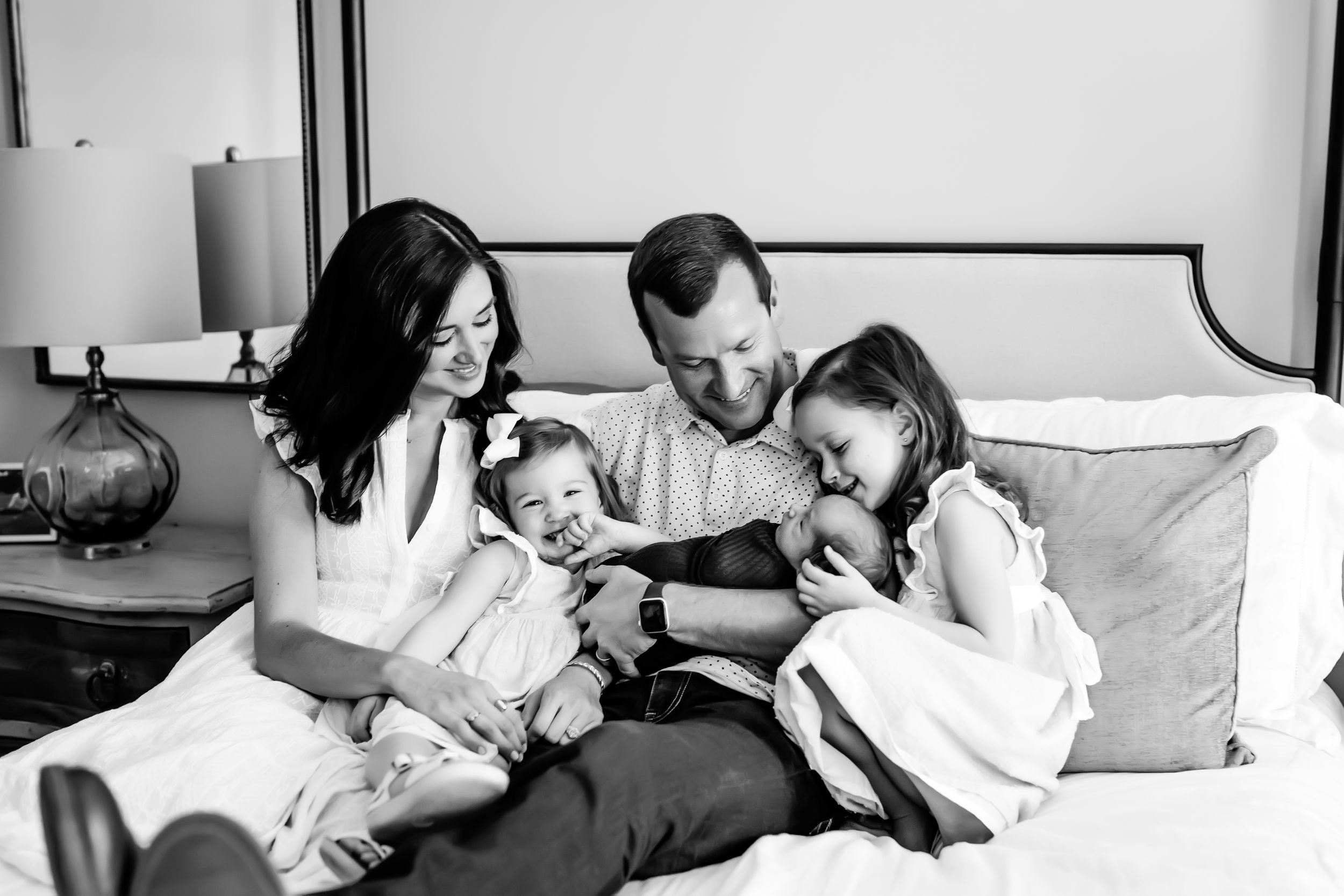 Black and white photo of a family sharing an intimate moment on a bed.