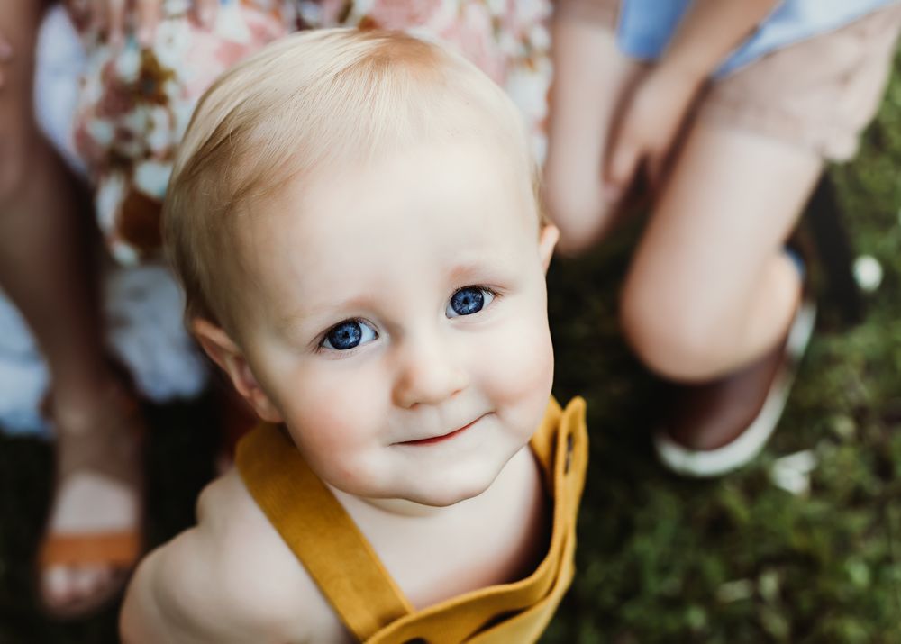 Close-up portrait of baby wearing yellow clothing with bright blue eyes.