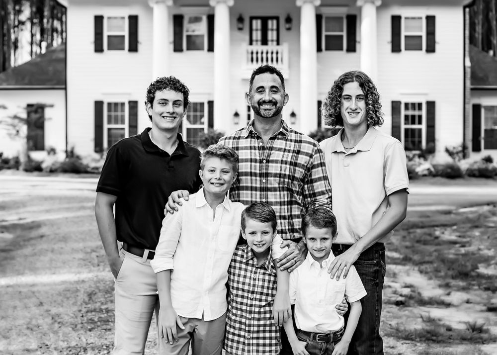 Group portrait in black and white in front of a white colonial style house.