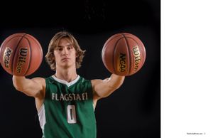 Basketball player in green jersey holding two basketballs against black background.