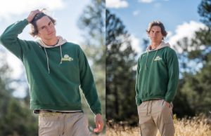Outdoor portraits in green hoodie against pine tree background.