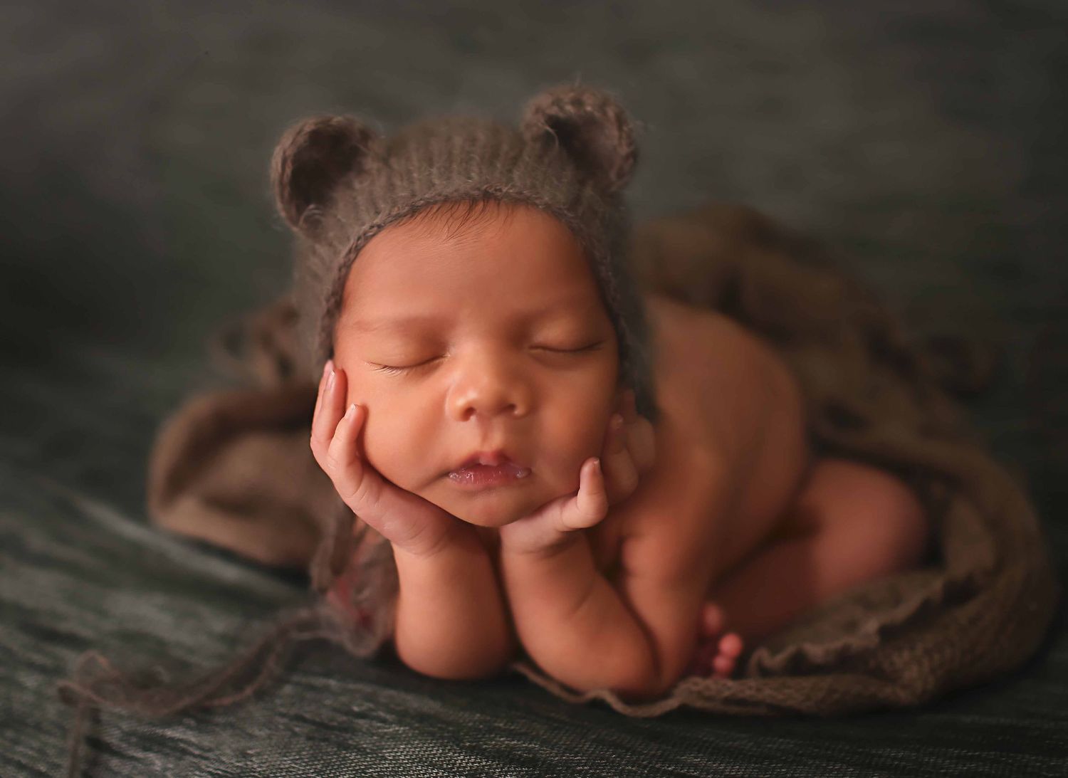 Newborn baby boy wearing brown bear bonnet at Alvin Tx studio