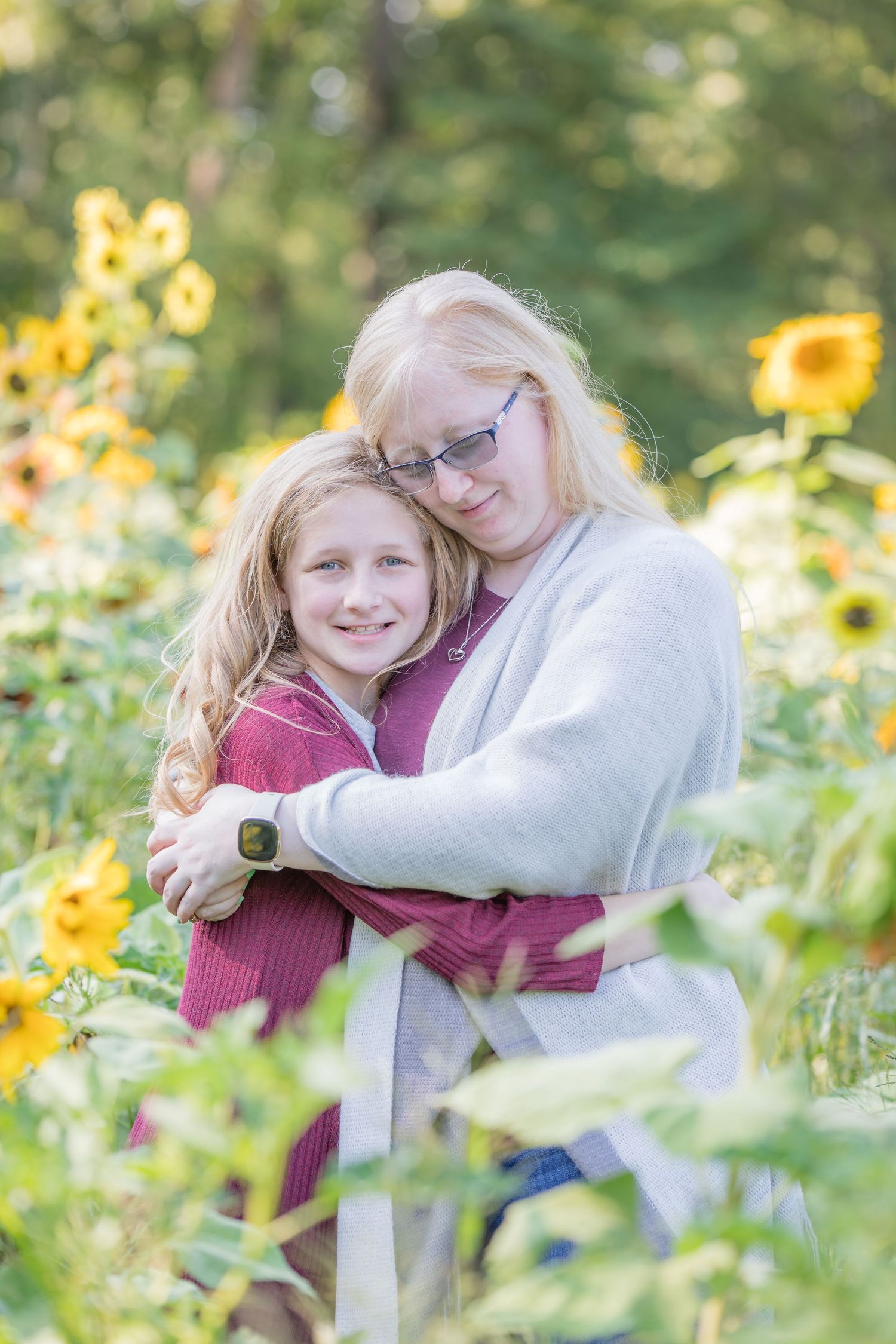 mother and daughter embracing in sunflower field at Ward's Farm in Salem New Jersey in bright sunlight