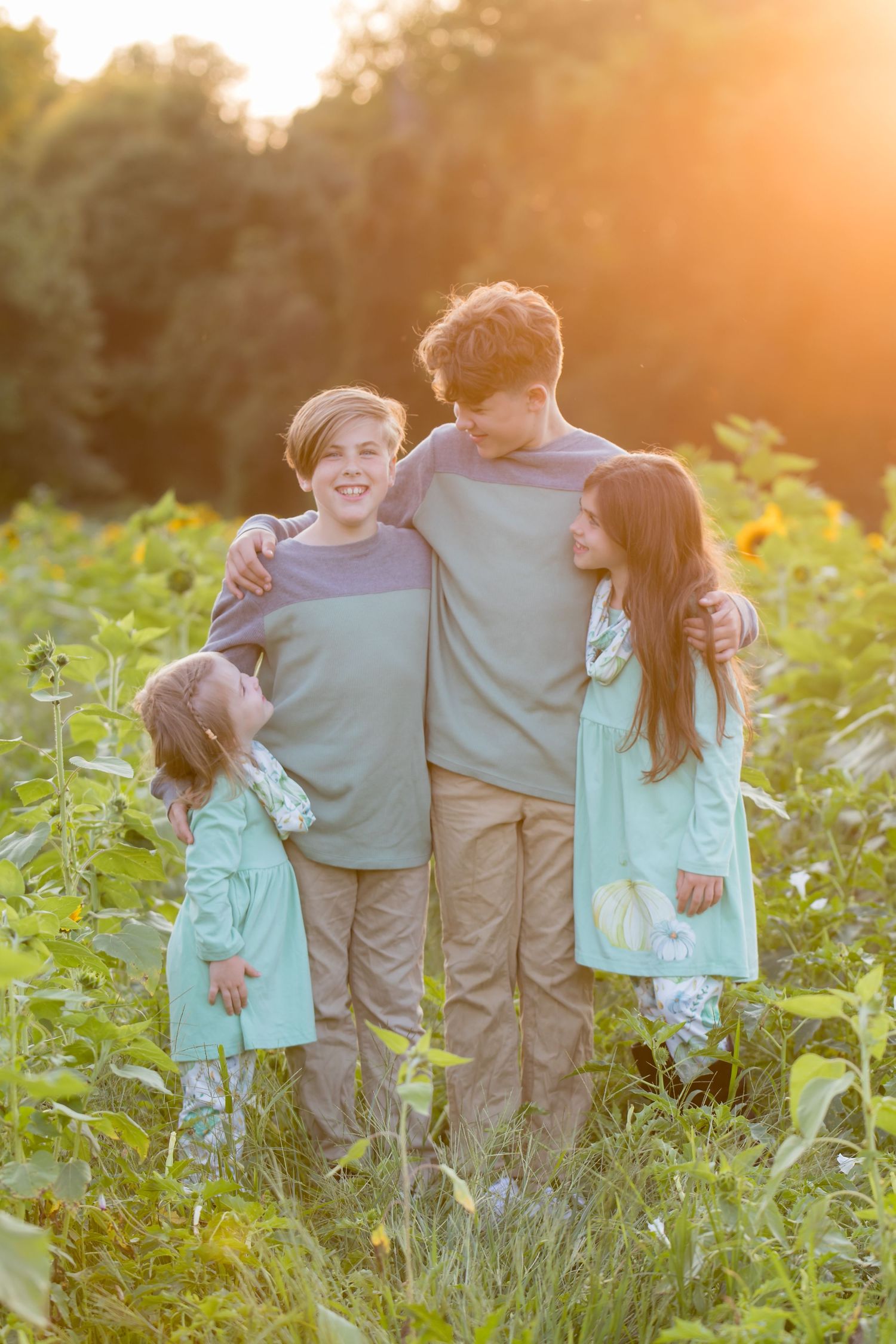 group of four children looking at each other in sunflower field at Ward's Farm in Salem New Jersey at sunset