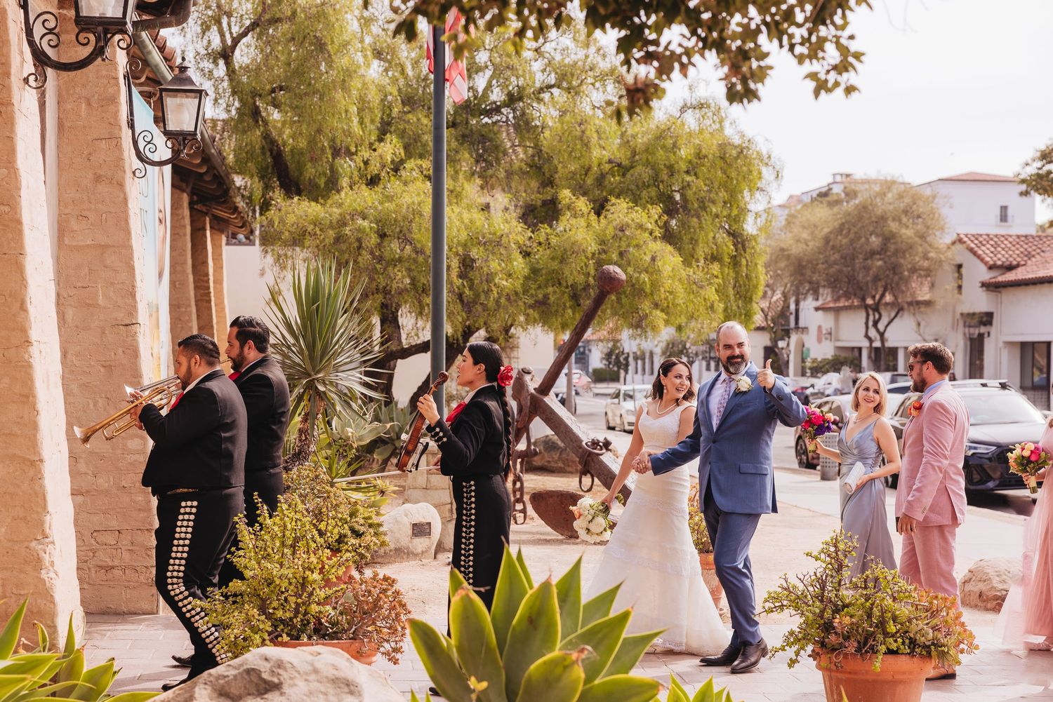Wedding party walking together on a sun-lit path with desert landscaping.