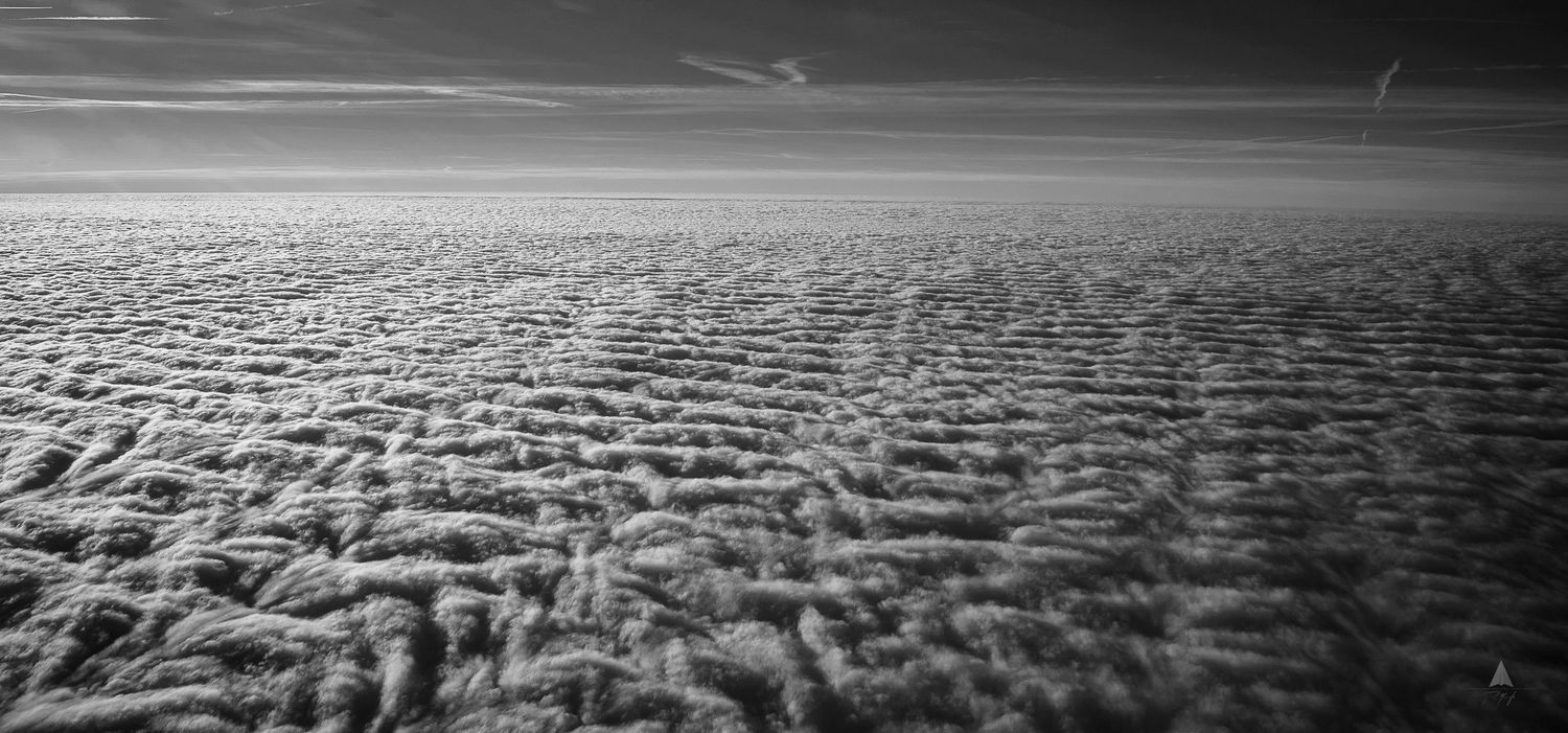Aerial black and white view of textured cloud formations stretching to the horizon.