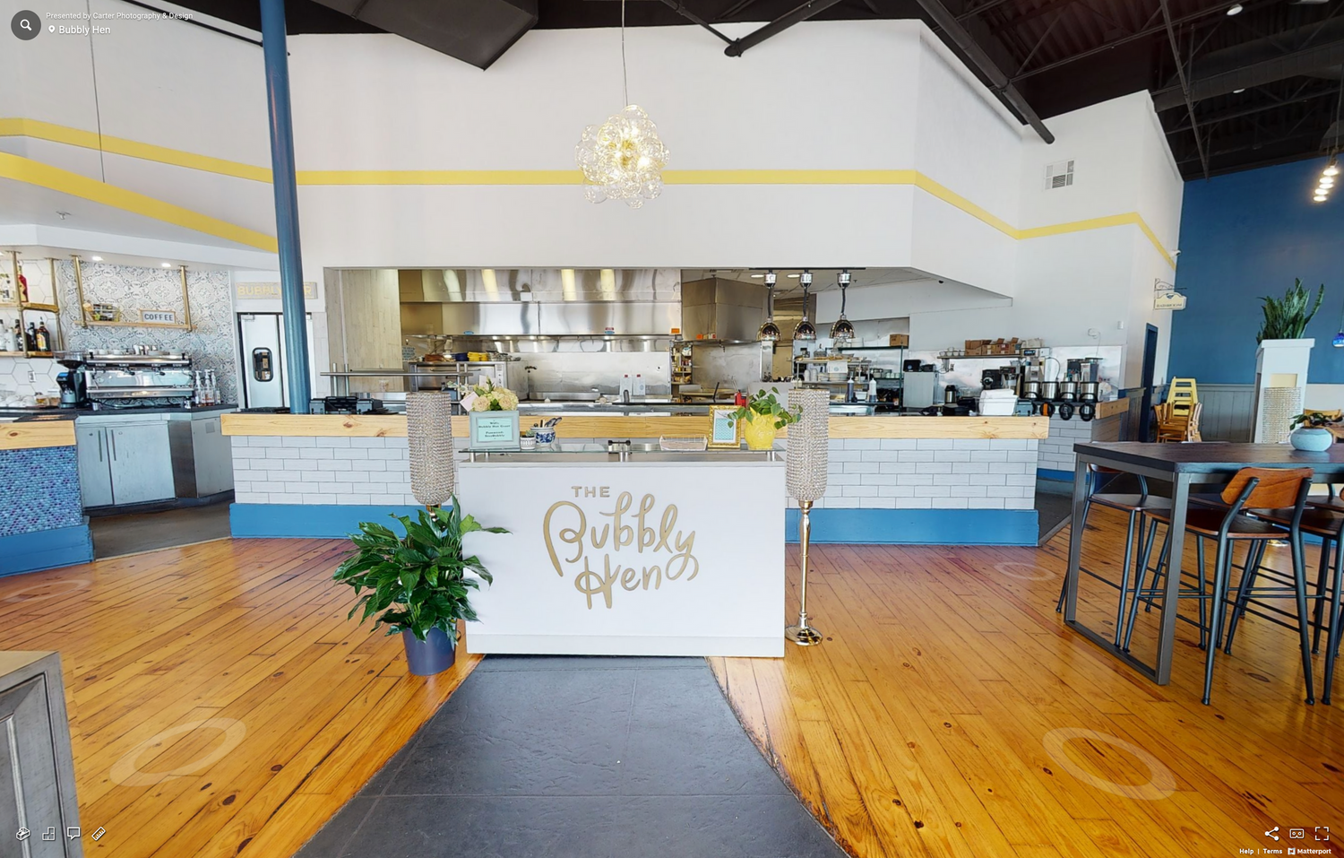 Modern cafe interior with wooden floors and a white service counter featuring a stylish gold sign.