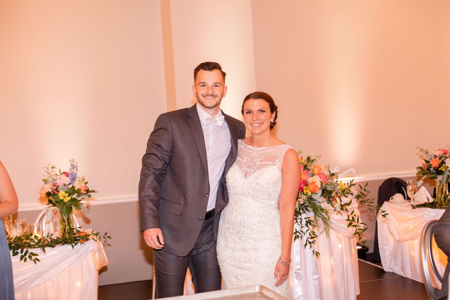 Wedding celebration in an elegant ballroom with warm peach lighting and white decor.