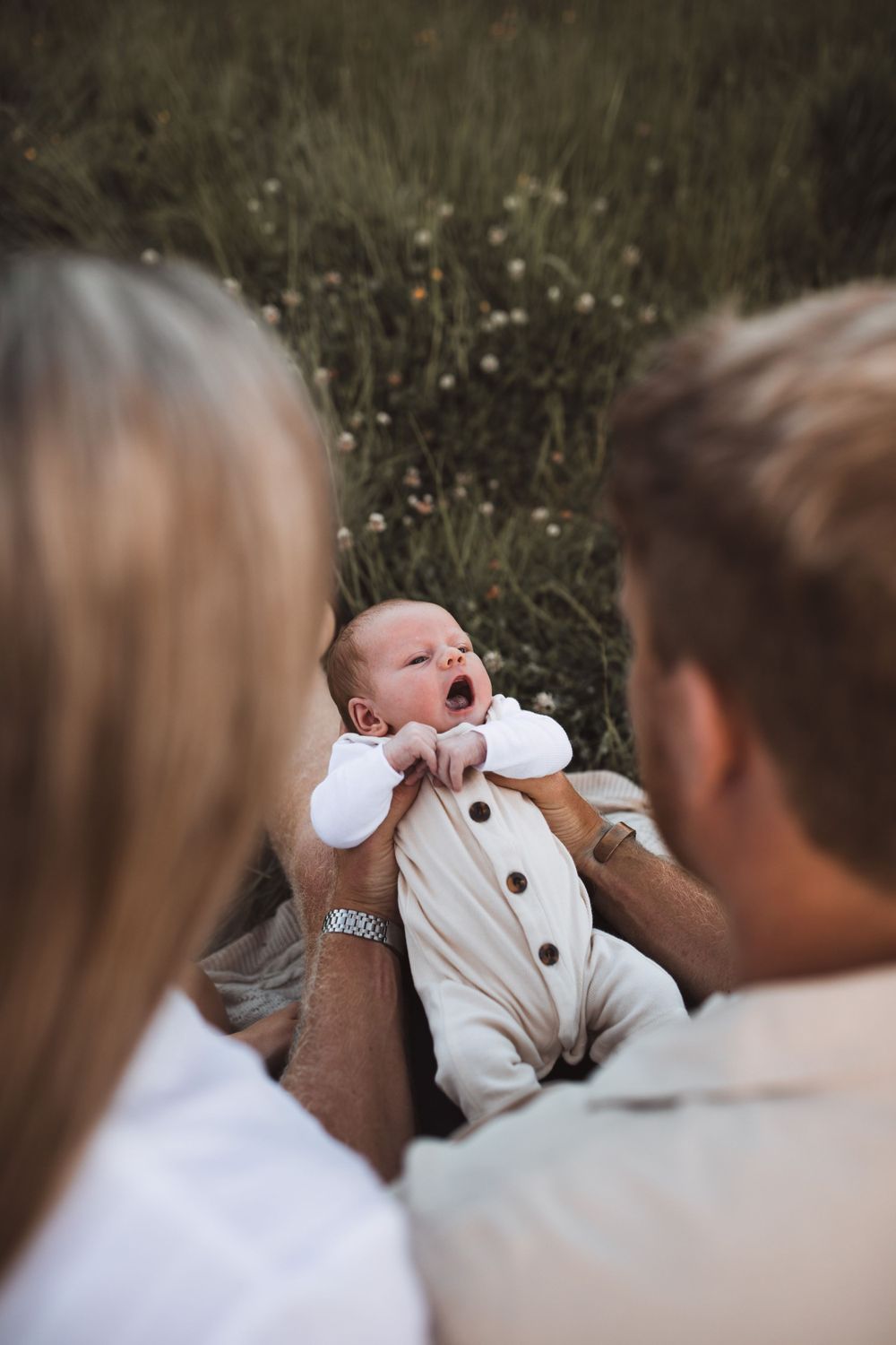 Close-up shot of tender family interaction with infant outdoors in natural lighting.
