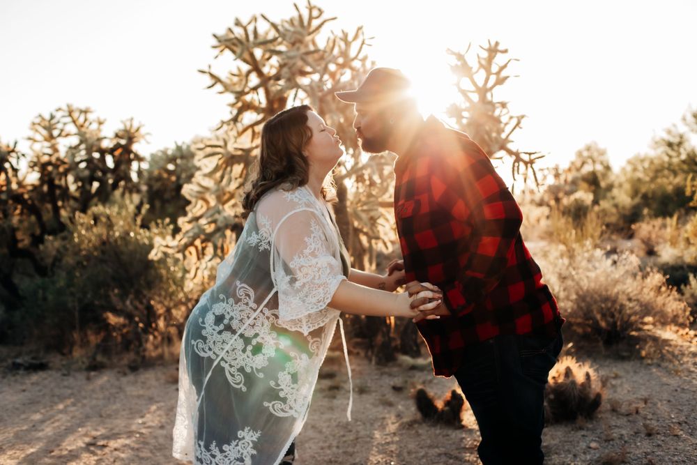 Romantic desert photoshoot with sunlight streaming through cacti branches.