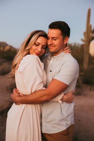 Romantic couple embracing in desert setting during golden hour.