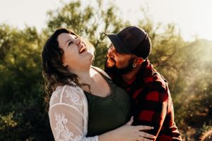Romantic couple's photography session in white and burgundy attire against desert backdrop.
