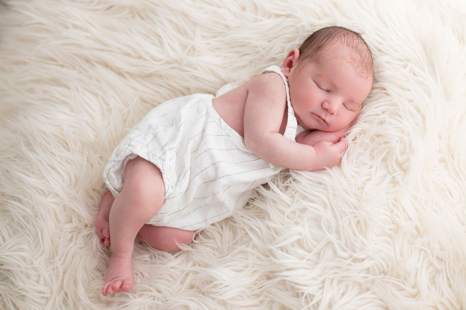 Newborn baby photographed on fluffy background at Little Wonderland Photography, Widnes, Cheshire