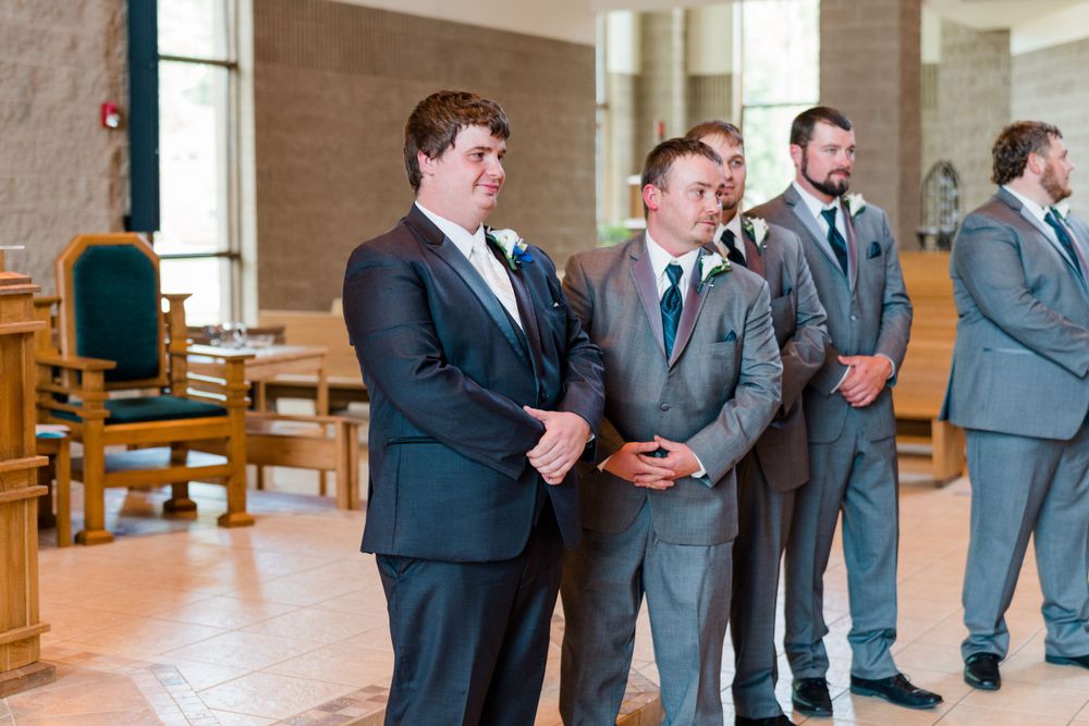 Groomsmen in grey suits standing in a church before the ceremony.