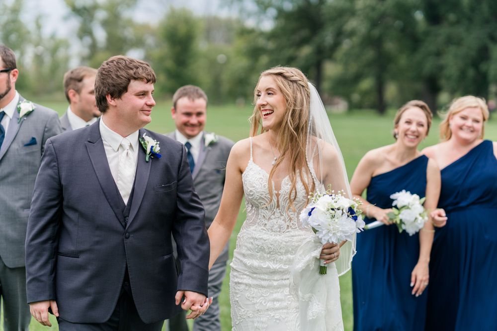 Joyful wedding party laughs together while walking outdoors.