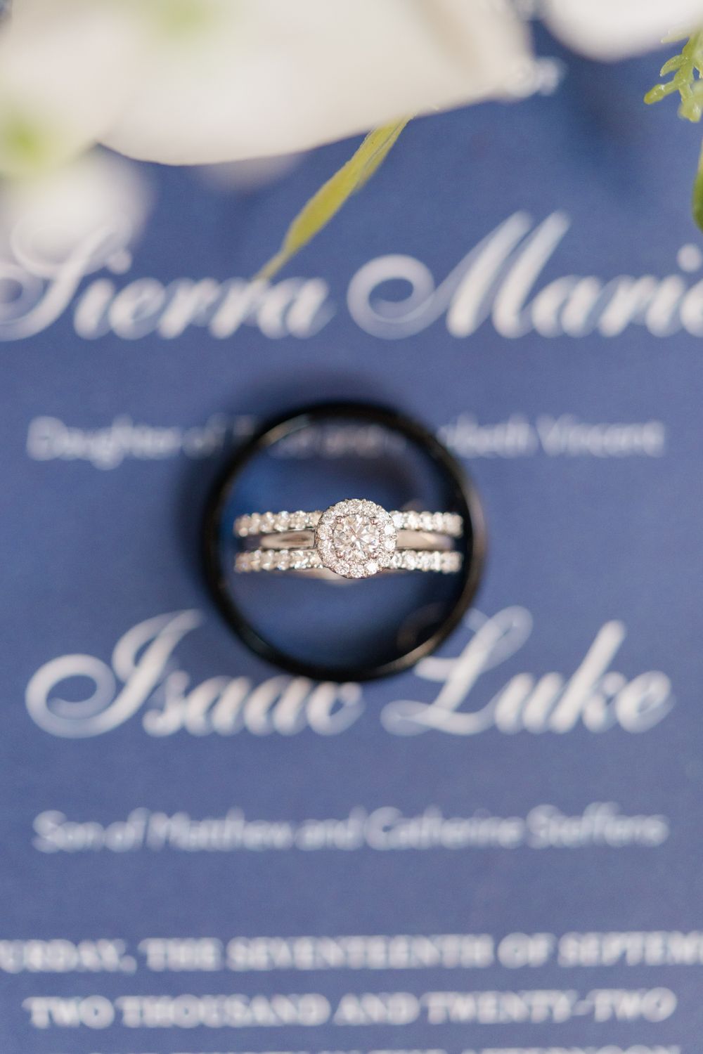 Wedding invitation details with diamond engagement ring photographed through black ring.
