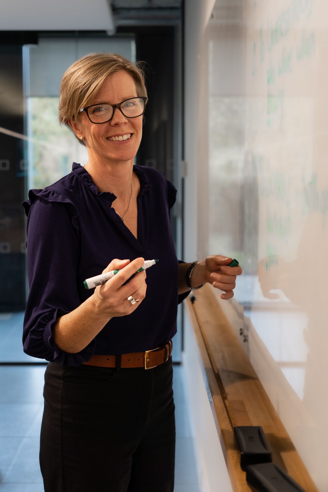 coach woman standing at whiteboard smiling