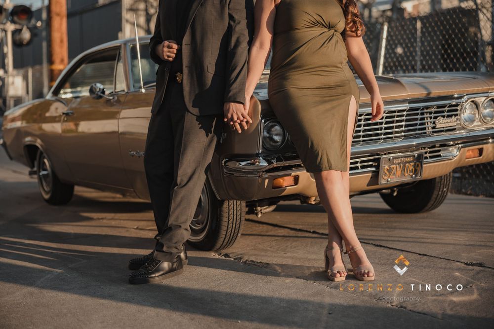 Couple holding hands next to vintage car during golden hour street photoshoot.