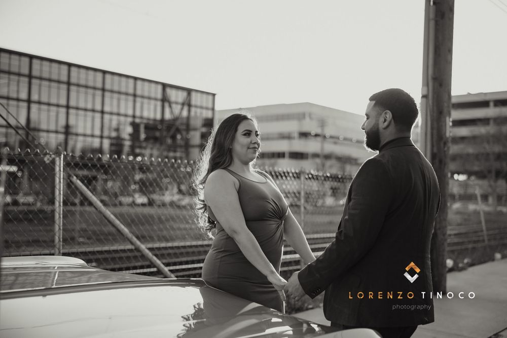 Black and white portrait of couple against industrial urban backdrop.