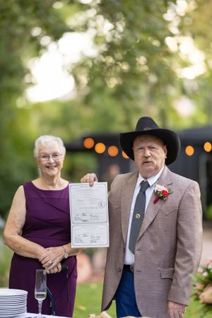 Wedding couple holding up their certificate of marriage smiling at the camera.