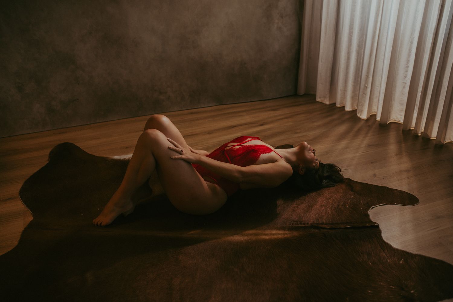 Moody indoor boudoir photography with soft lighting and dark tones.