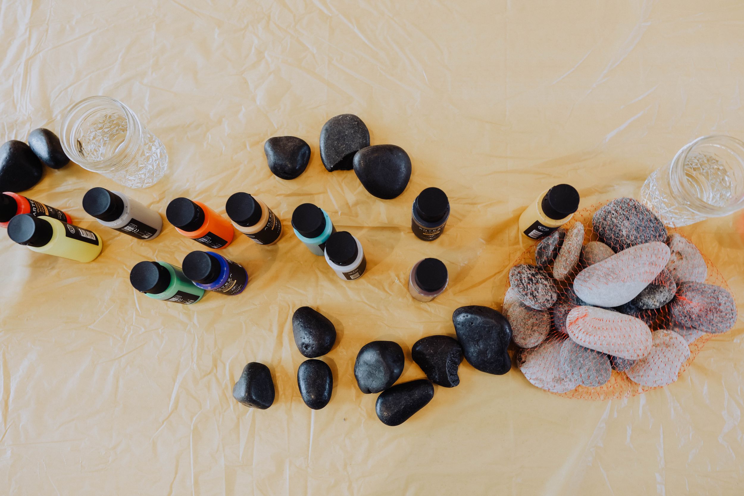 Smooth black and gray stones arranged artistically on a light yellow surface.