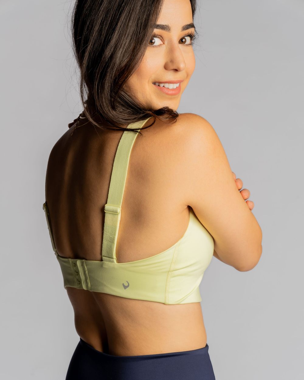 Sports bra in light green color shown from back view against gray background. Handful brand photography with Fleck of Light.