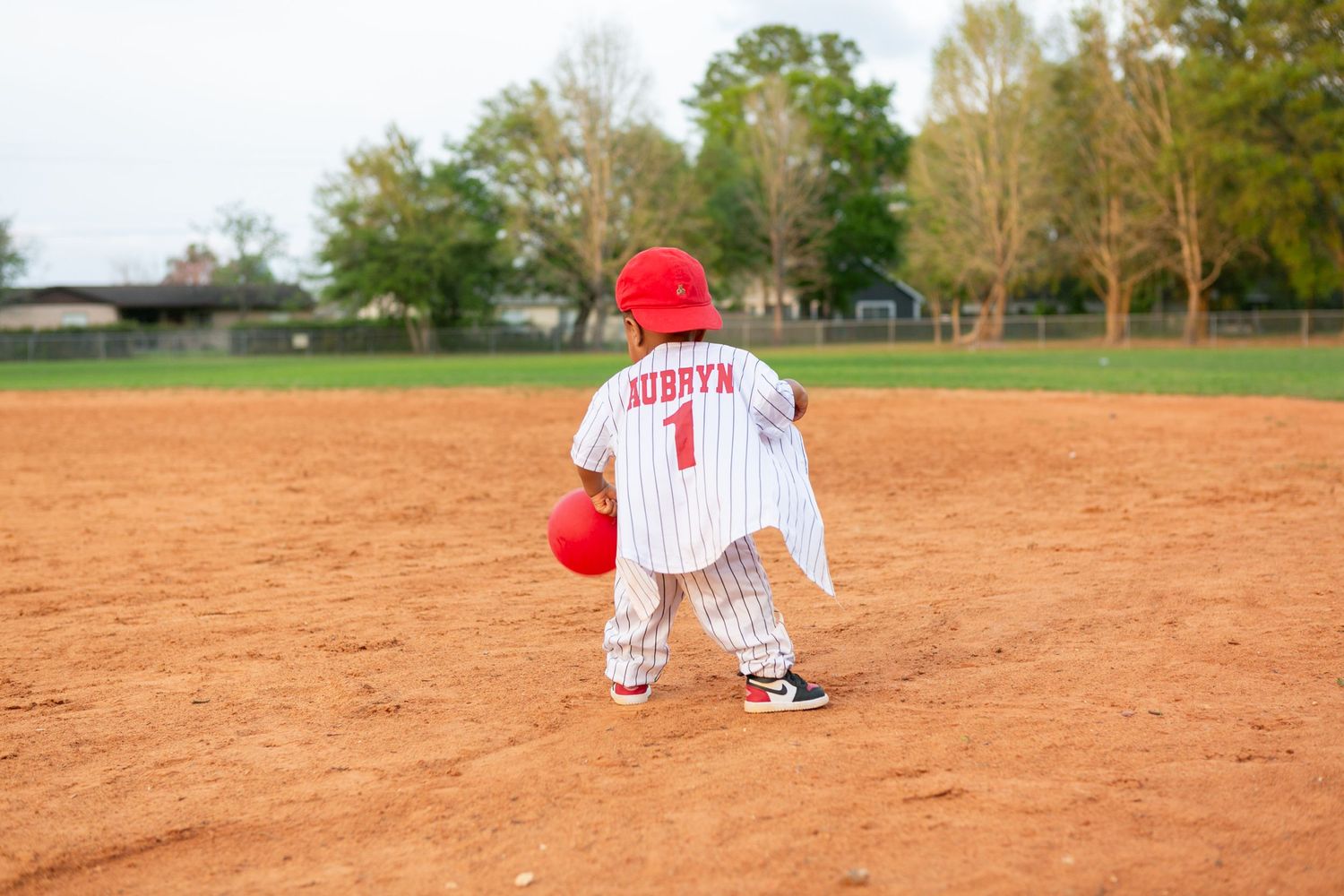Sanford FL Cake Smash Photography baby boy walking on the baseball field for his first birthday