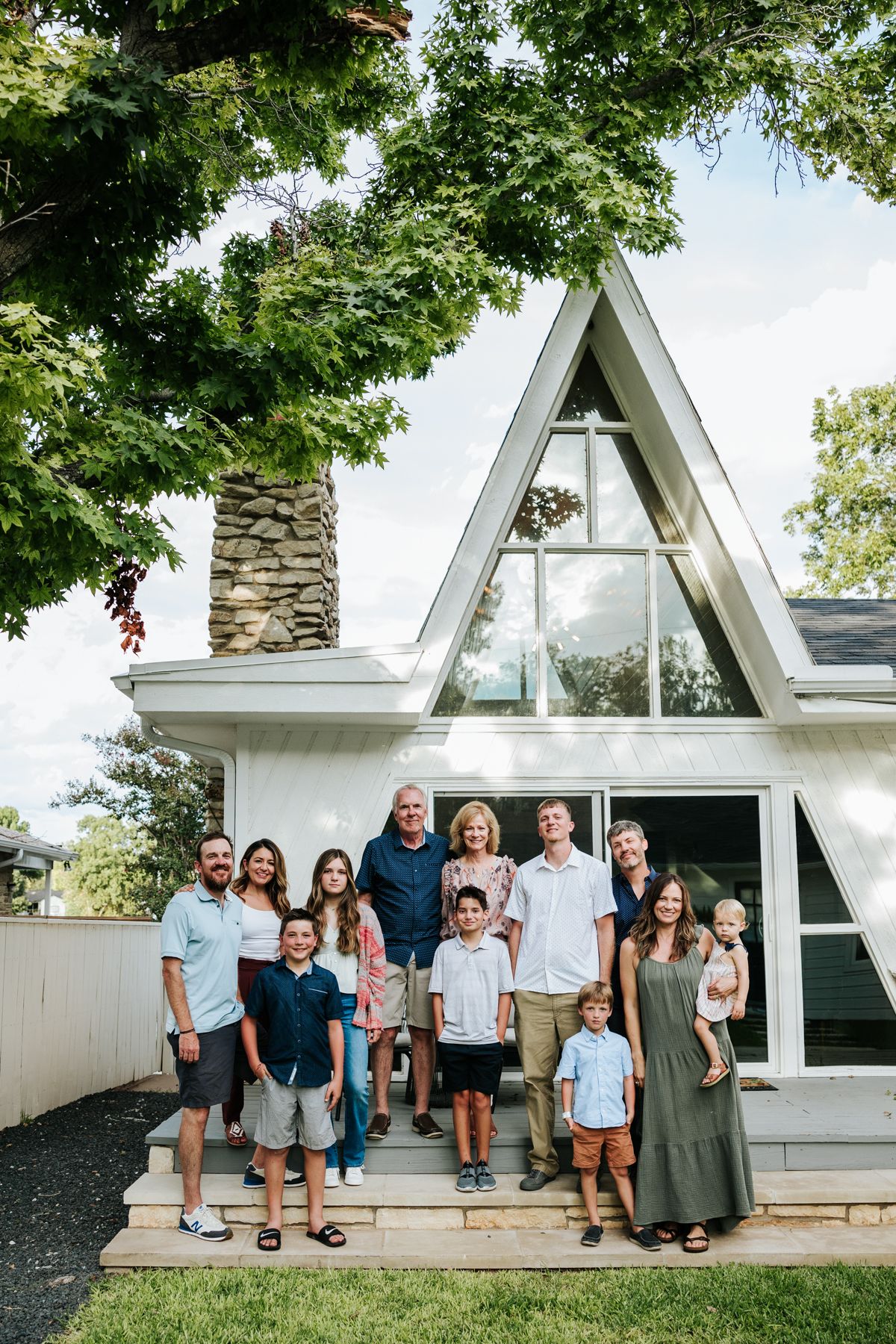 family standing on porch of A frame house with parents grandparents children and babies