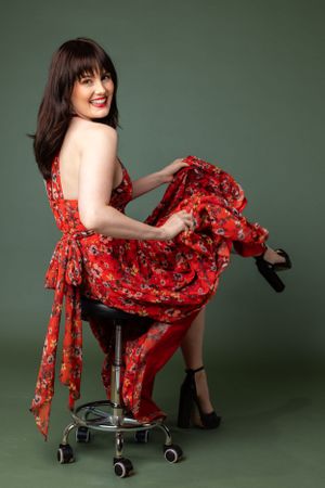Studio fashion photo featuring a floral red dress against a green background.