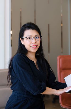 Business professional in navy attire seated with documents in modern office setting.