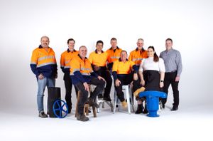 Team photo of workers in high-visibility orange uniforms against white background.