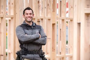 Construction professional in work gear standing in front of wooden framework.