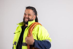Industrial worker wearing high-visibility safety vest and hardhat posing confidently.