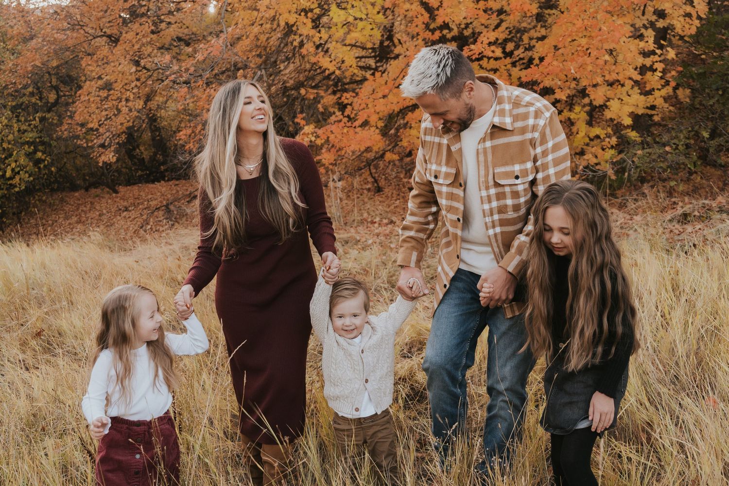 A family laughs together during their fall photoshoot with their children and toddlers.
