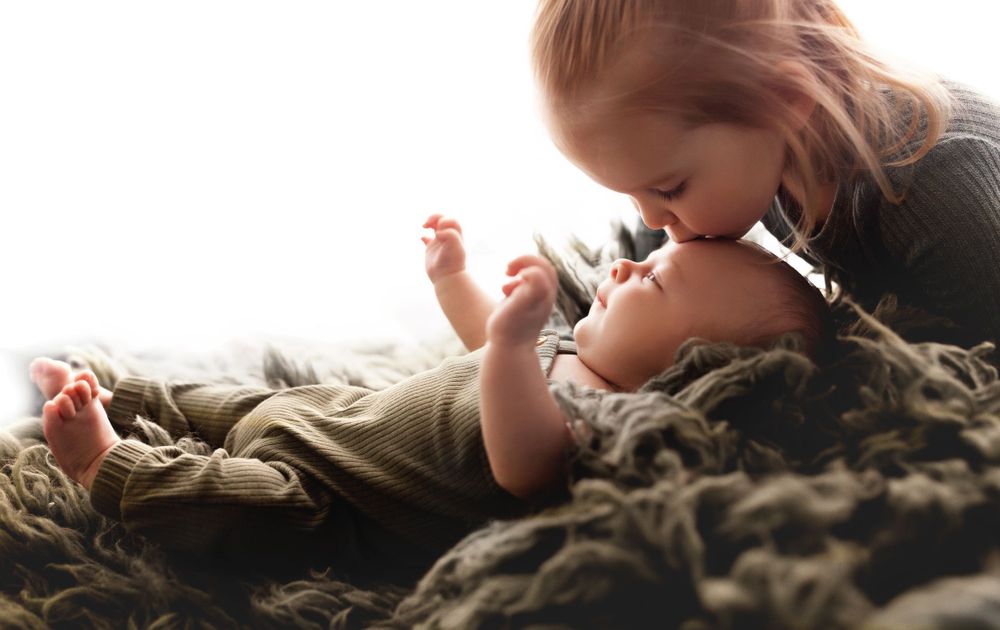 Tender moment captured between parent and infant on textured blanket.
