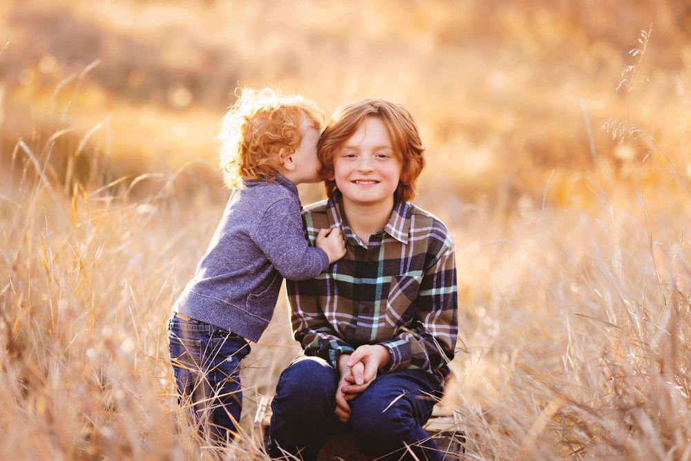 Sweet moment captured in golden hour with two people in a field of tall grass.
