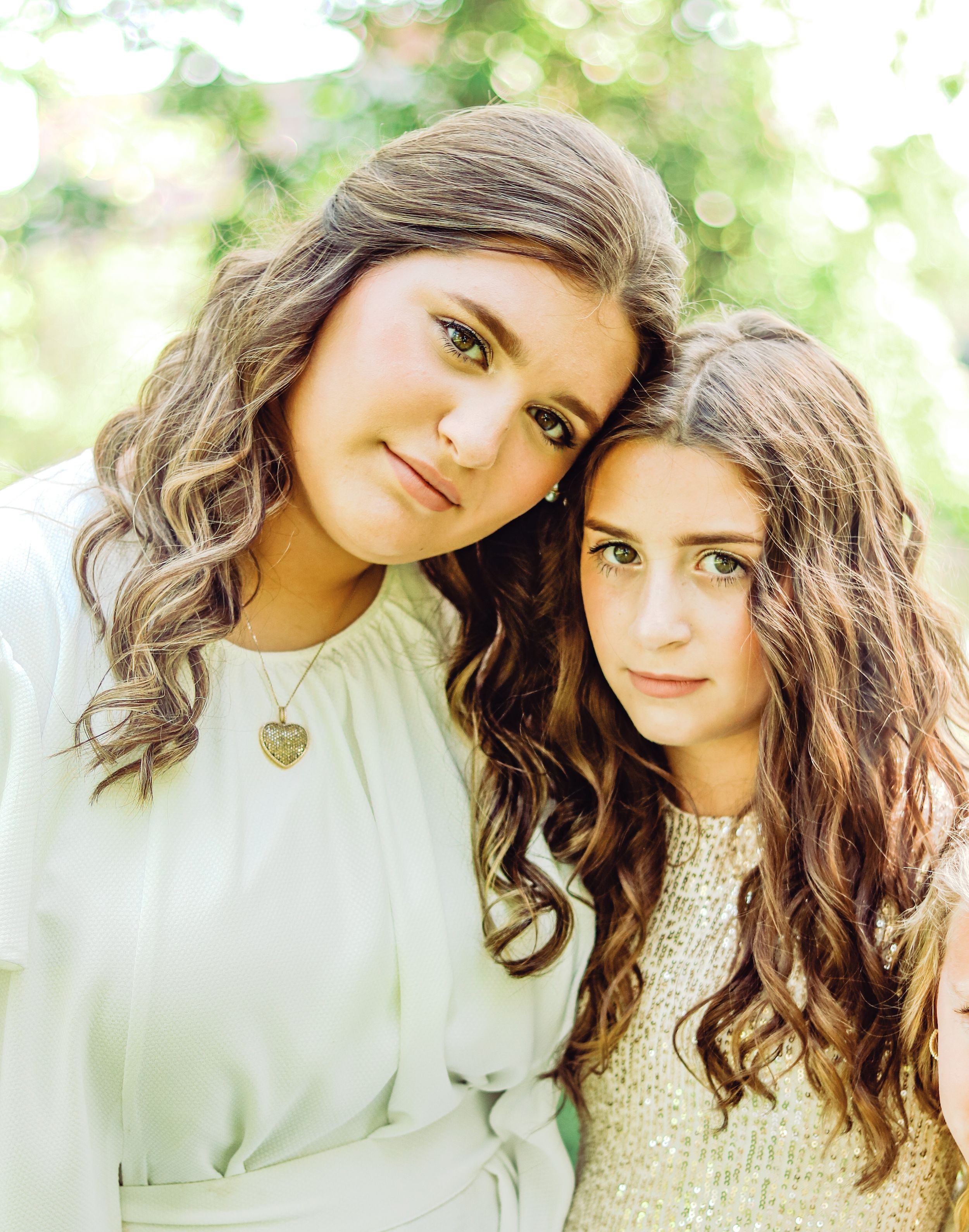 Two sisters posing seriously looking straight at the camera for their natural light portrait.