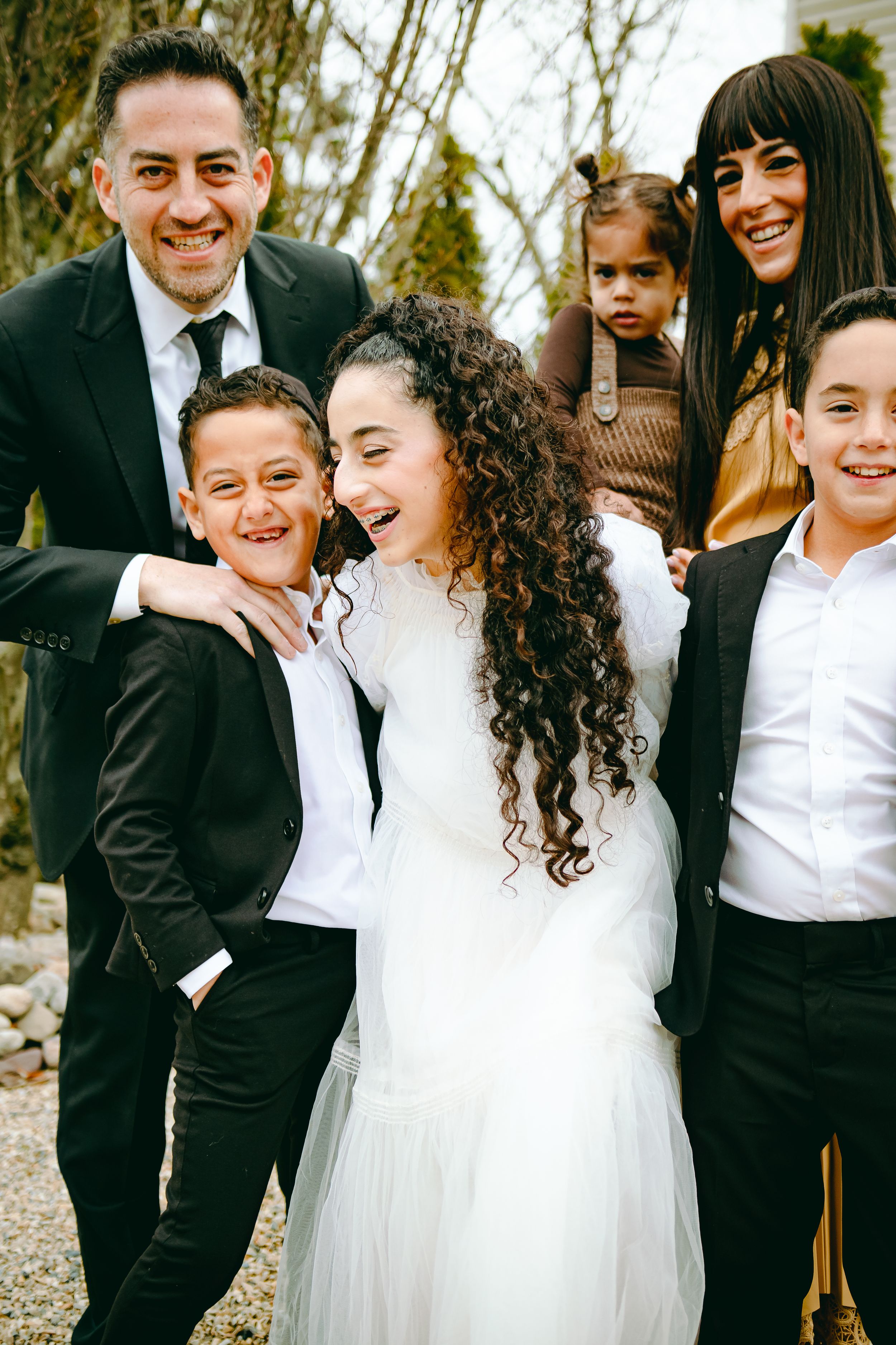 Large family laughing and hugging each other outside their home in Jackson, NJ during a professional in-home photoshoot