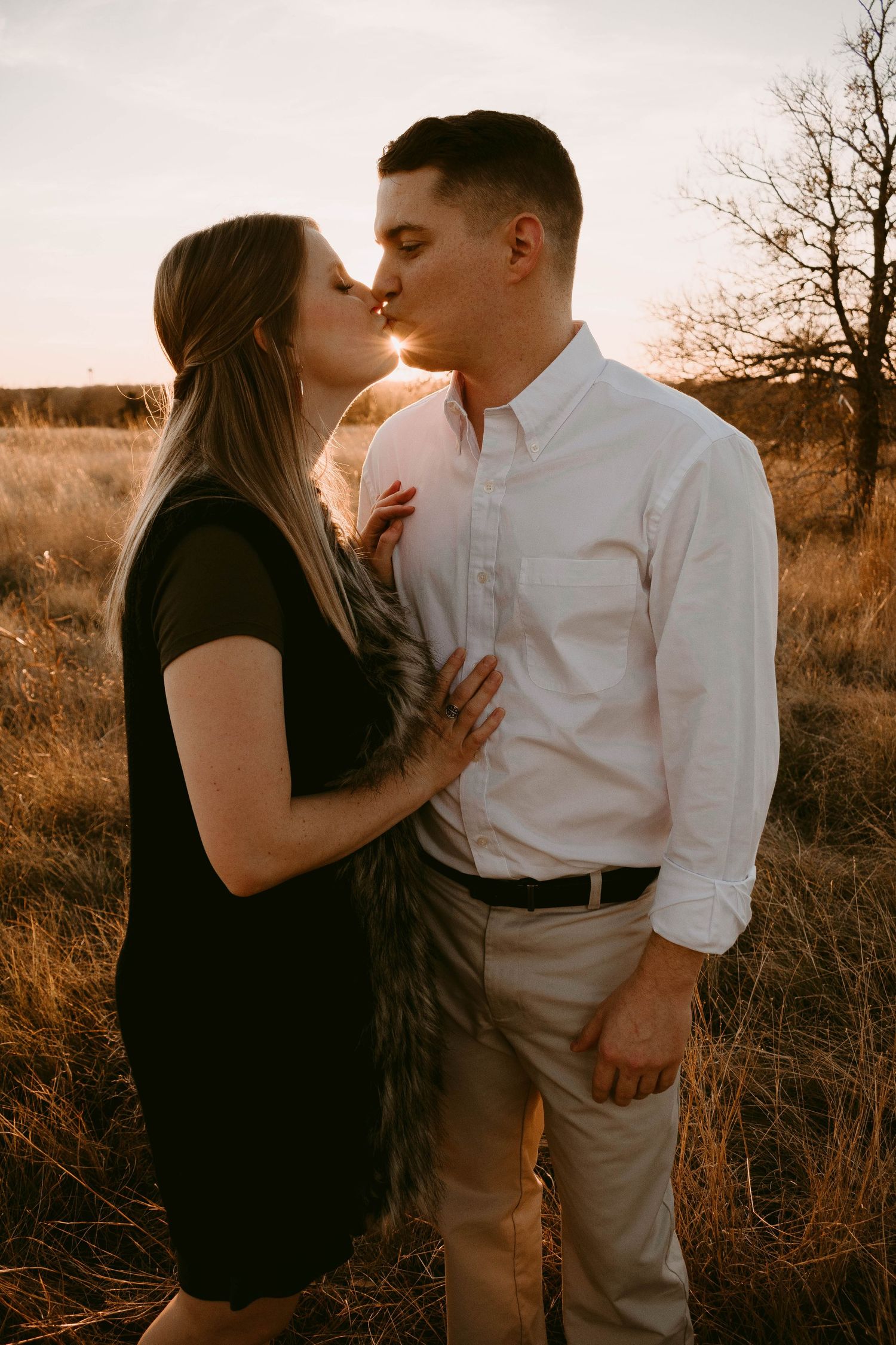 Intimate close-up of a couple about to kiss in a golden field at sunset.