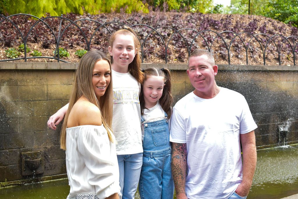 Family group photos taken outdoors by water with natural greenery backdrop.