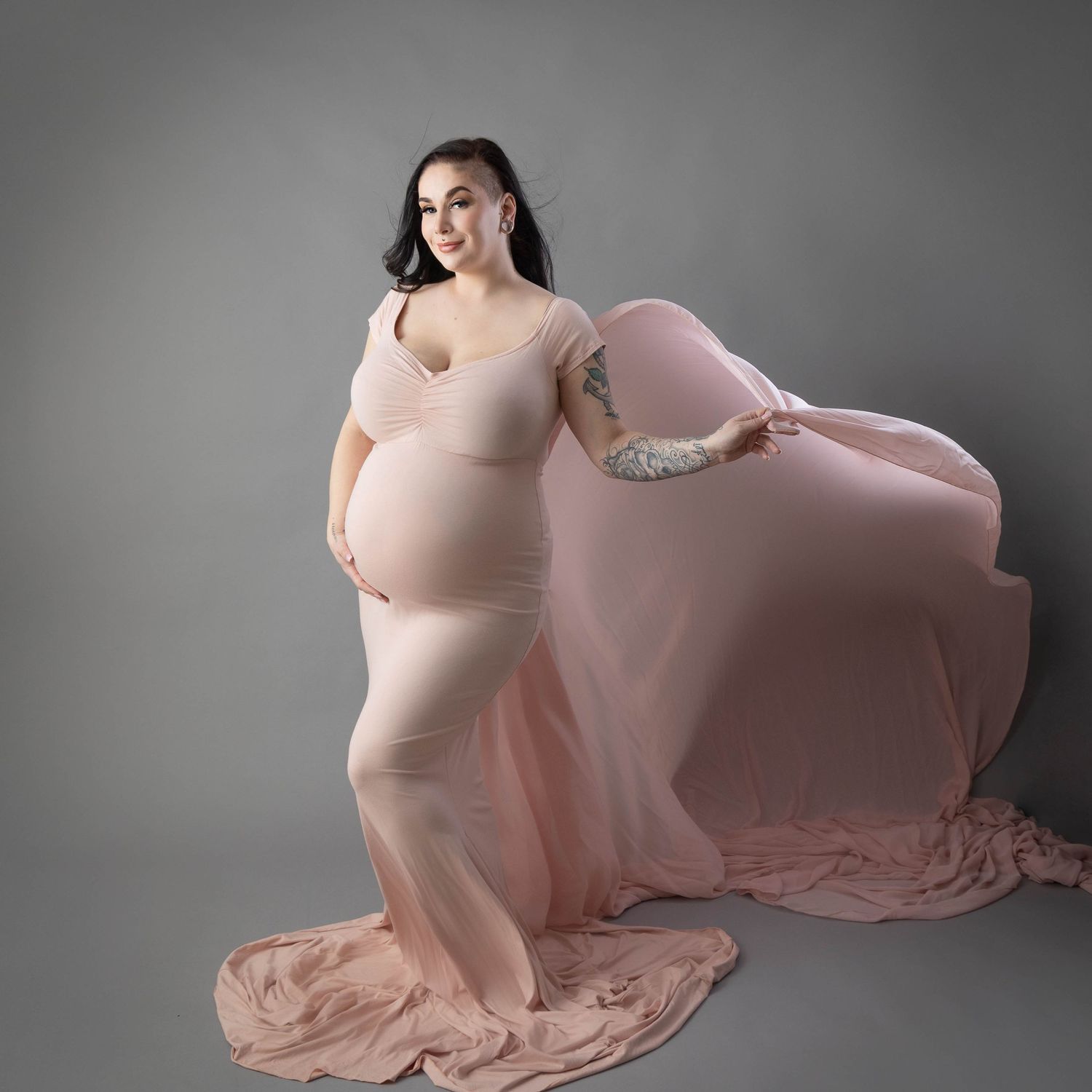 Studio maternity portrait in form-fitting dusty rose dress with flowing train.