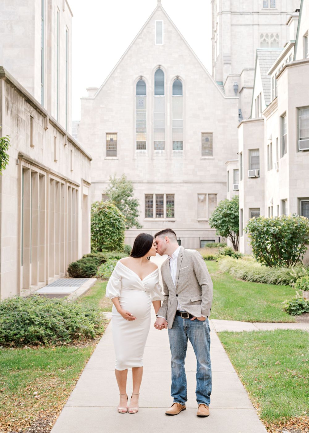 Expecting couple walking together on path in front of church building.